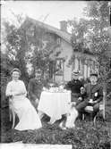 Augusta Lundin, stinsen Per August Svensson, hans hustru Eva Karolina Pettersson och deras son August Natanel vid kaffebordet i trädgården, Bärby järnvägsstation, Funbo socken, Uppland före 1929