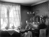 Sömmerskan Anna Wester i sitt rum på andra våningen i bönhuset, Åby, Funbo socken, Uppland före år 1900