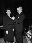 Kvinna får medalj av landshövding Hilding Kjellman, sannolikt i universitetsaulan, Uppsala augusti 1946