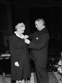 Kvinna får medalj av landshövding Hilding Kjellman, sannolikt i universitetsaulan, Uppsala augusti 1946