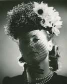 Porträtt av kvinna i hatt med flor och blomstergarneringar, av Monsieur Erik.