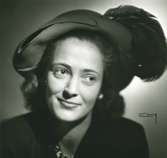 Porträtt av kvinna med hatt i röd filt med fjäder. Hatt använd vid franska avdelningens uppvisning september 1947.