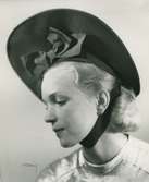 Fb, Porträtt av kvinna i hatt av Madame Alphonsine. Svart filt med hakband.