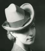 Fb, Porträtt av kvinna i hatt av Madame Le Monnier. Grå filt med lila band.