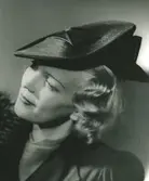 Fb, Porträtt av kvinna i hatt av Jeanne Lanvin. Svart stråhatt med garnering av svart blankt band.