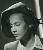 Porträtt av kvinna i grå enkel uppslagen filthatt. Modell från Jacques Fath.