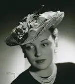 Porträtt av kvinna med rosa stråhatt, monterad med äppelblomma och tyll. Modell från Nordiska Kompaniet.