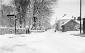 Kungsgatan mot norr. Till vänster syns kvarteret Kronofogden med gamla kyrkogården. Vid gatans slut syns Varbergs kyrka. Fototid: 1900-tal. Vinter, snö. I högerkanten en stolpe (ellednings-?)