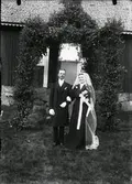 Bröllpsfoto på Maria och Alfred Karlsson framför en äreport.