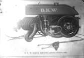Text på glasplåten: D K W. Motorn sedd från cykelns vänstra sida.