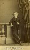Porträtt av Adolf Rydholm som barn. Han står lutad mot ett räcke och håller i ett gevär.