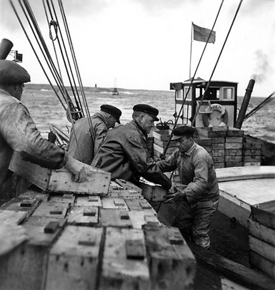 Olof Hasslöf, The cargo is taken on board in the “follower,” Oden - Gravarne, for rapid transport to the factory. Fr.v.: Valter Askman, Per Karlsson, Albert Amandusson, the man on the right belongs to the crew of Oden.