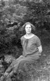 Kvinna sittandes i skogsparti