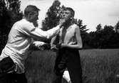 Gustav Andersson (1) och annan ung man involverade i låtasasboxning, i bakgrunden lövträd. Lungkliniken, Eksjö.
Fotografens anmärkning: Knockoutmarchen mellan Dempse v Johansson.