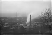 Vy över bebyggelse med industrier och höga skorstenar.
