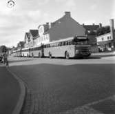 Utefter Rosenborgsgatan i Huskvarna står en rad abonnerade bussar ,längst fram en Scania-Vabis från 1956.