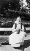 Äldre kvinna som sitter på en bänk vid Kärra Hökegård, ett försörjningshem för såväl senildementa som psykiskt sjuka, utvecklingsstörda och ensamstående mödrar. Verksamheten försvann i och med att Lackarebäckshemmet stod klart 1951.