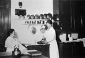 Husmor fru Jönsson med kokerskan Ida Talinsson (från Hultet i Kållered) i köket på Stretereds skolhem 1926.