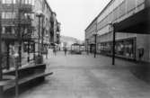 Till vänster, längst ner mot Göteborgsvägen, ses Brogatans äldsta stenhus Centrumhuset, 1980-tal. Till höger ligger gamla Hantverkshuset med bank och post. Gatan hette då Frölundagatan.