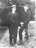 Två yngre herrar, en med studentmössa och en med keps. Omkring 1900-talet.
Mycket bleknat fotografi. Okänd ort.