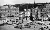 Stora Torget med torghandel och Gustav Adolfstatyn i förgrunden, till vänster Hirschska huset (kv Nyttan) och till höger Holmströmska huset (kv Hälsan). Text på vykortet 