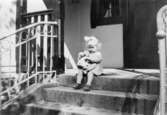 Inga-Lill Lipovsék, 4 år, sitter på en trappveranda med en docka i famnen, 1951. Hon bodde på Stretereds vårdhem från två års ålder.