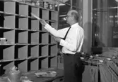 Förste postiljon Lennart Viktor Nilsson på postkontoret Solna 1, sorterar brev.