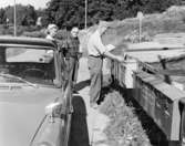 Bilåkande lantbrevbäraren Erik Johansson lämnar post i en brevlådesamling i Skeppsdal på linjen Åkersberga-Singö-Björnhuvud-Åkersberga.

Foto augusti 1961.