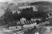 Flygfoto över Forsåkers fabriker vid Grevedämmet i Mölndal, 1930-tal. I bakgrunden ses Stensjön och villan Stensjöhill. Fabriksbyggnaden kallades tidigare för Bettyholm och  Carlsfors fabriker. Relaterade motiv: 1993_0162 - 0164.