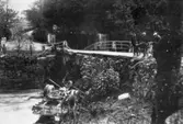 En lastbil som har kört ned i Lindomeån vid gamla stenbron. 1920-tal.