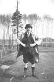 Helmer Garthmans kompis Charlie Jinnerstedt, ståendes i ett avverkat skogsområde, har dragit upp kostymbyxorna. Göteborg, 1940-tal.