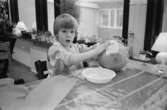 En pojke sitter vid ett bord, inomhus på Katrinebergs daghem, och limmar silkespapper på en uppblåst ballong. Limmet ligger på en plasttallrik framför honom och han tittar mot kameran.