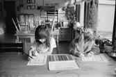 Cecilia och Jessika sitter vid ett bord och färglägger med hjälp av färgpennor, förtryckta figurer på var sitt A4-blad. Båda är mycket koncentrerade. Lunkentussen, Katrinebergs daghem 1992.