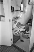 Två pojkar sitter på tre mindre madrasser i ett rum och bläddrar i var sin bok. De är fotograferade ifrån ett intilliggande rum, genom en dörr-öppning, och de sitter precis innanför. Katrinebergs daghem, 1992.