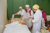 Julmarknad på Mölndals museum 1994-12-04. Tre förklädds-försedda kvinnor bakar.