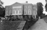 Trädgårdsarkitektbesök på Gunnebo slott den 26 augusti 1939. Exteriör från söder. Slottsbyggnaden syns utan altan med balustrad och trappor ned till trädgården. Dessa togs bort i slutet av 1800-talet, men återuppfördes i sten 1955-1956.