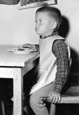 En pojke som sitter och äter. Holtermanska daghemmet 1953.