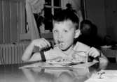 En pojke som äter mat. Holtermanska daghemmet 1953.