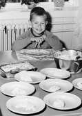 En pojke som sitter vid ett dukat matbord. Holtermanska daghemmet 1953.