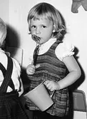 En flicka (Marita Björk, född Andersson) ståendes med en skål i ena handen och en visp i den andra. Holtermanska daghemmet 1953.