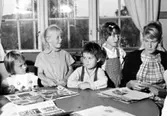 Lärarinna och dagbarn pysslar vid ett bord. Holtermanska daghemmet 1953.
