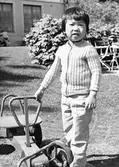 Ett barn som står utomhus med en trampbil. Holtermanska daghemmet juni 1973.