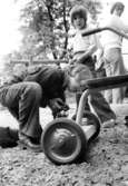 En pojke smörjer hjulet på en trehjuling. Holtermanska daghemmet 1973.