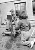 Två barn som leker med en grävskopa i sandlådan. Holtermanska daghemmet juni 1974.