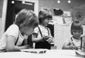 Två barn som ritar och ett barn tittar på. Holtermanska daghemmet maj 1975.