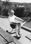 En flicka som cyklar på en trehjuling. Holtermanska daghemmet, okänt årtal.