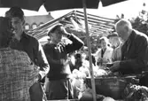 Torghandel på Nya torget, 1960-tal. Man ser Evert Andersson (i keps) från Fässberg Västergården. I bakgrunden skymtar taket på Kvarnbyskolan.