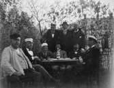 Nio medlemmar i Storviks postklubb fotograferade i
Överliggningslokalens trädgård i Storvik, juni 1900. Sittande från
vänster: Fanjunkaren, Kalle P-s, Jockus, Pliggen, Magnus, Carl
Kihlberg. Stående från vänster: 