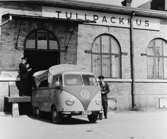 Chauffören Einar Andersson lämnar Tullkammaren där han lämnat
paket, som prickats in av 1:e tulluppsyningsman Ernst Hofvensten
(t.v.). Postlastbilen är av märket Volkswagen.