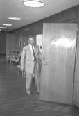En kostymklädd man står vid en halvöppen dörr. Mölndals stadshus, juni 1994.